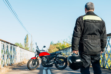 man on his back looking at a motorcycle with a helmet in his hand
