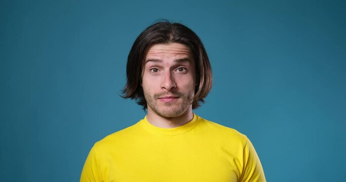 Confused man looking with raised eyebrow over blue background
