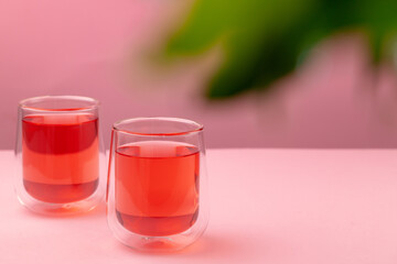 Two glass cups of black tea on beige table