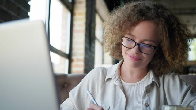 online session, pretty girl undergoes remote education and communicates with teacher via communication while sitting at laptop in cafe