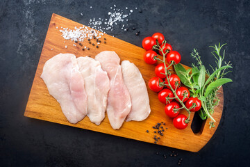 Raw traditional chicken escalope with tomatoes and herbs offered as top view on a modern design...