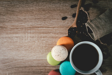 Black Coffee in a cup with coffee beans and macarons on wood table background