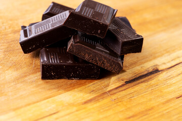 Dark chocolate pieces isolated on wooden background