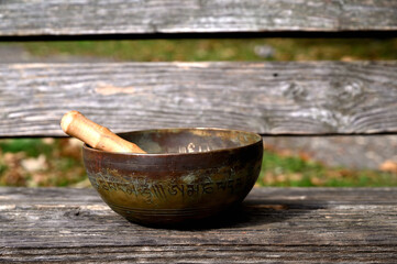 Tibetan singing bowl. on a wooden bench. Translation of mantras. transform your impure body, speech and mind