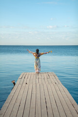 modest girl in a hat near the seashore on the beach, against the blue sky