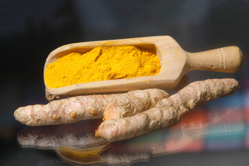 Turmeric powder (Kurkuma) in a wooden spoon and roots