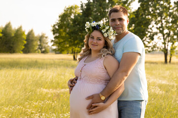 A pregnant woman with her husband is resting in nature.