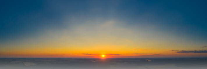 Panoramic image of a warm red sunset with rays of sun over the autumn mist