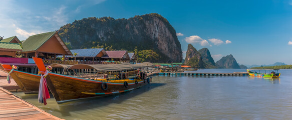 Fototapeta na wymiar Traditional longtailed speed boats moored at the jetty of the settlement of Ko Panyi in Phang Nga Bay, Thailand