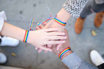 Hands of a group of three people with LGBT flag bracelets. LGBT pride celebration.