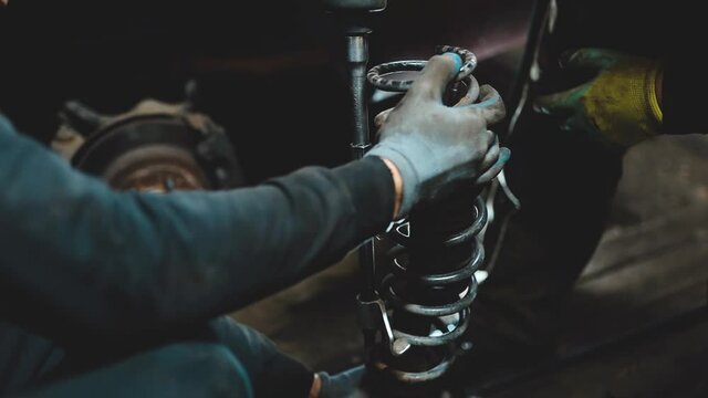 Auto mechanics compress the spring with zip ties to replace the shock absorber. Car suspension repair.