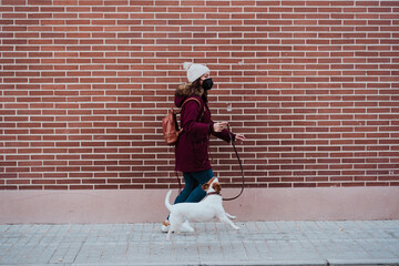 Fototapeta na wymiar woman wearing protective mask walking at the city with her adorable jack russell dog. Lifestyle outdoors