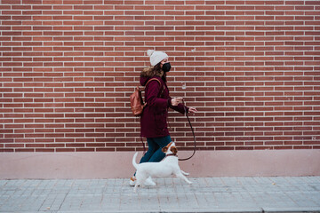 woman wearing protective mask walking at the city with her adorable jack russell dog. Lifestyle outdoors