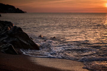 Fototapeta premium Sunrise with orange colors on the beach of Sant Pol de Mar (Barcelona)