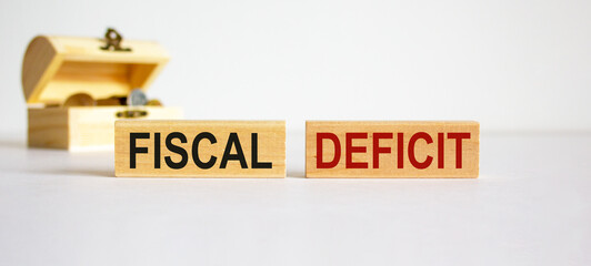 Concept words 'fiscal deficit' on blocks on a beautiful white background, small chest with coins. Business concept, copy space.