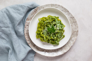 pasta with spinach on a light background, top view