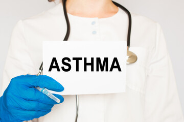 The doctor's blue - gloved hands show the word ASTHMA - . a gloved hand on a white background. Medical concept. the medicine