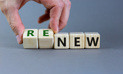 Time to renew. The words 'new' and 'renew' on wooden cubes. Male hand.  Beautiful grey background, copy space.