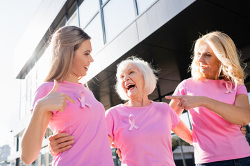 Women laughing and pointing with fingers at sign of breast cancer awareness