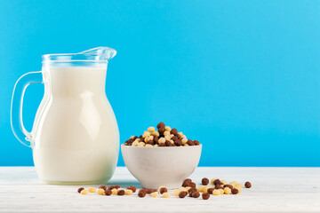 Breakfast cereal balls and milk in glass against blue background