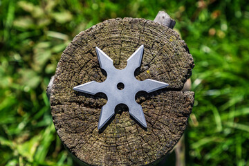 Shuriken (throwing star), traditional japanese ninja cold weapon stuck in wooden background © Sergii