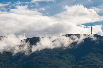 A peak on Vitosha mountain in Bulgaria surrounded by white clouds like mist. Blue sky with clouds. Beautiful landscape.