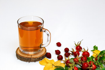 healthy rosehip tea in a glass Cup on a wooden saw, next to dry and fresh rosehip berries on a white surface