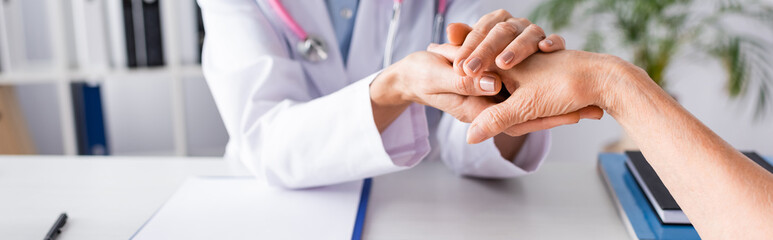 Panoramic shot of doctor with stethoscope comforting patient in clinic