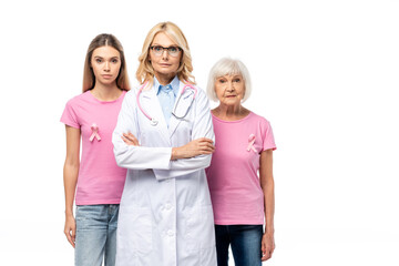 Doctor with crossed arms standing near women with pink ribbons on t-shirts isolated on white