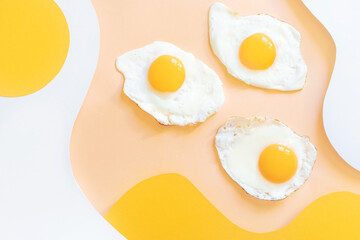 Fried eggs on a light white and yellow wavy background. Paper art. Breakfast concept, fried food.