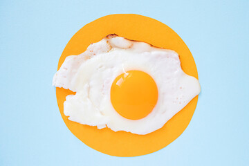 Fried eggs on a light orange and blue background, pattern. Breakfast concept, fried food. Minimalism, top view.