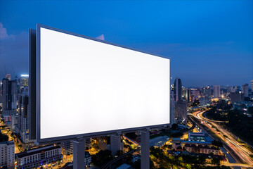 Blank white road billboard with KL cityscape background at night time. Street advertising poster, mock up, 3D rendering. Side view. The concept of marketing communication to promote or sell idea.