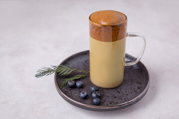 Korean coffee Dalgona Original colors, colored milk in a glass cup on a light background with a place for text. New Year's drink. Good New Year spirit