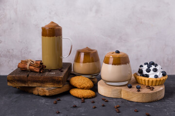 Korean Dalgona coffee, colored milk, with whipped foam. Cookies, chocolate, cake. Composition with coffee drinks and dessert. Good New Year spirit. Copy space