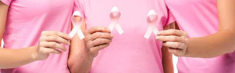 Panoramic shot of women holding pink ribbons of breast cancer awareness isolated on white