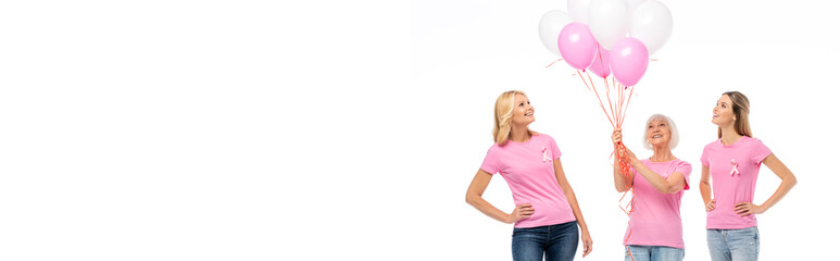 Fototapeta premium Panoramic shot of women with pink ribbons looking at balloons isolated on white