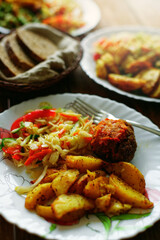 A simple meal on a plate at a diner. Salad, fried potatoes and meat cutlet. Quick and delicious lunch