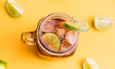 ice tea with slice of lemon in mason jar on bright yellow background. Top view composition slices of lemons