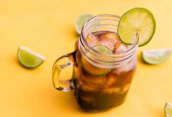 ice tea with slice of lemon in mason jar on bright yellow background. Top view composition slices of lemons