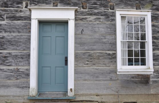 Vintage blue door with white frame and window frame  on a wooden building made of weathered wood