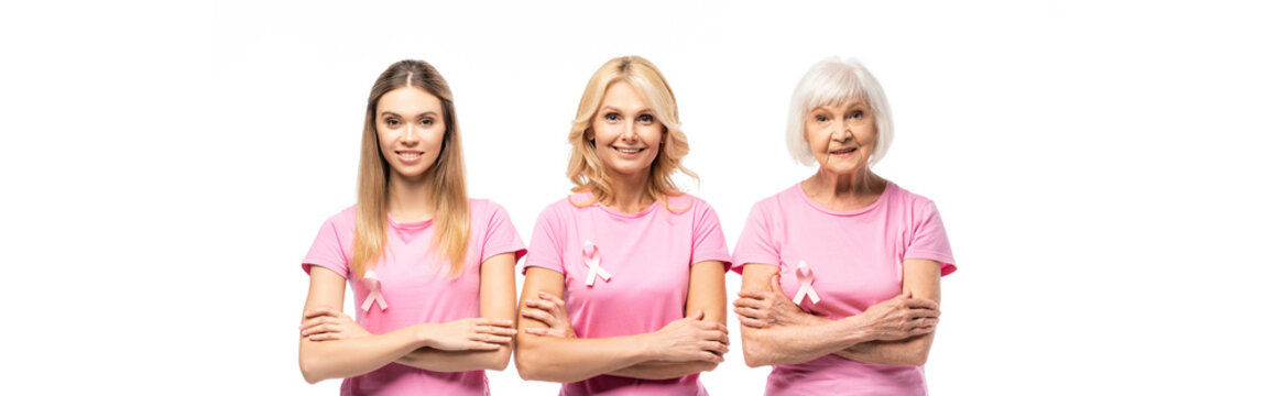 Horizontal image of women in pink t-shirts with breast cancer awareness ribbons looking at camera isolated on white