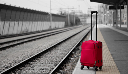 a red suitcase near the train tracks
