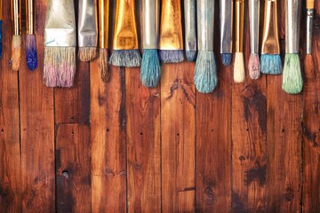 Row of artist paint brushes on wooden desk
