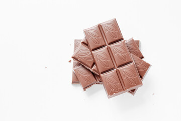 Milk chocolate pieces isolated on white background from top view, close up a chocolate bar isolated on white background