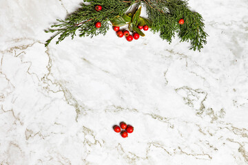 Christmas image/background.Pinophyta, brown pinecone with tree leaves, gift and red fruits on white marble.