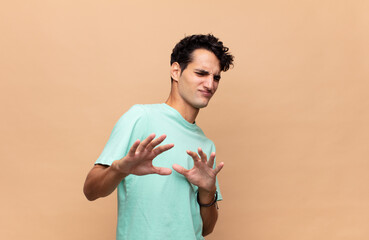 young handsome man feeling disgusted and nauseous, backing away from something nasty, smelly or...