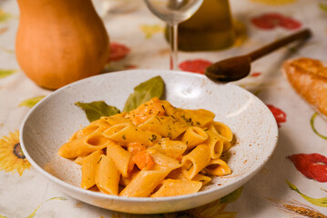 butternut squash pasta with creamy , fresh pumpkin sauce on white plate and colorful table cloth. Traditional italian autumn pasta