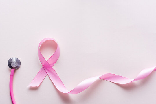 Close up view of pink ribbon near stethoscope isolated on white