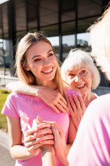 Selective focus of women embracing and holding hands, concept of breast cancer