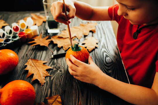 Child paints pumpkins for Halloween